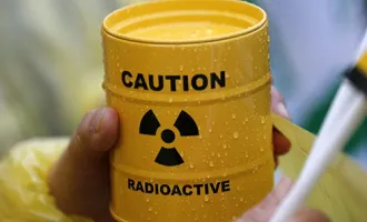 Hand holds canister with radioactive sign.