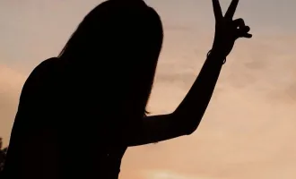 Silhouette of a woman flashing peace sign