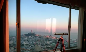 Telescope pointed out a window overlooking San Francisco.