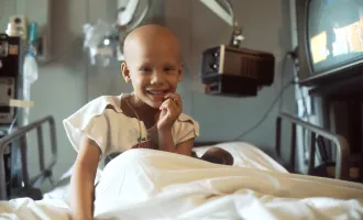 Smiling child cancer patient in gurney