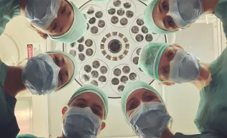 Surgeons looking downwards towards patient.