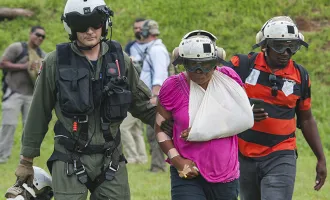 An aircrewman prepares an injured resident for evacuation.