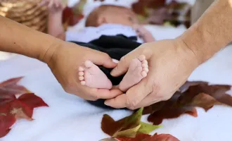 Two adult hands holding baby's feet.