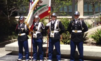 Four veterans in uniform, holding the California state flag, and US flag