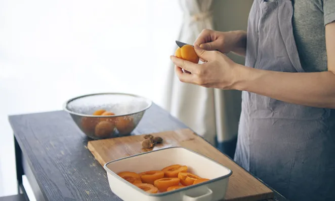 Hands slicing apricots.