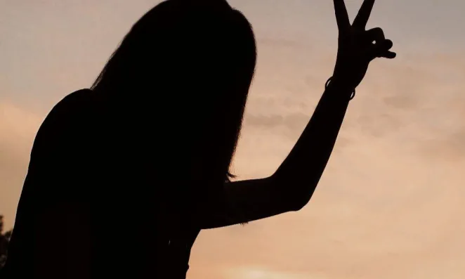 Silhouette of a woman flashing peace sign