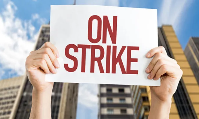 Hands holding sign reading on strike.