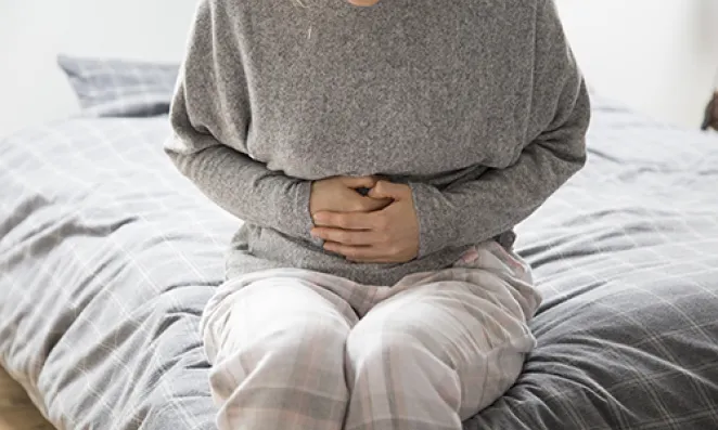 Woman with hands grasping stomach.