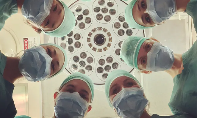 Surgeons looking downwards towards patient.