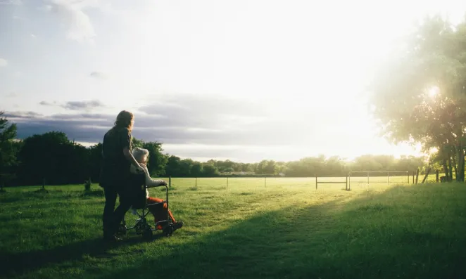 Woman pushing elderly person in wheelchair