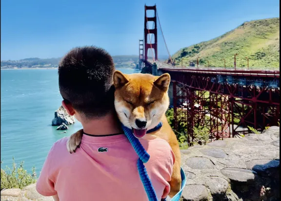 Man holding dog at Golden Gate Bridge.
