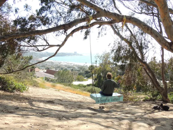 Woman sitting on a swing looking out towards the ocean.