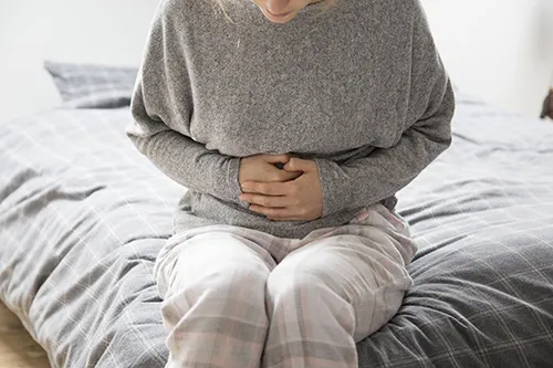 Woman with hands grasping stomach.