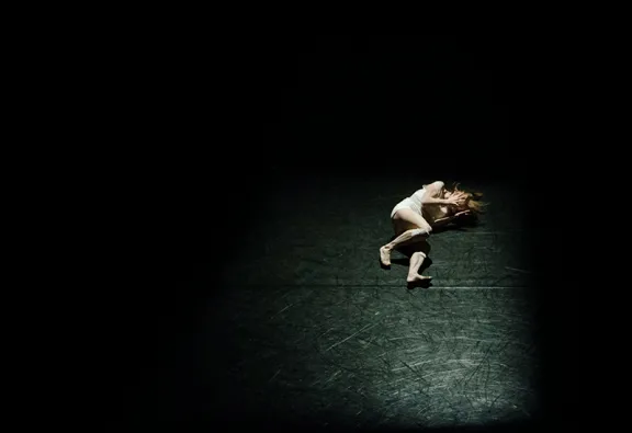 Woman clutching head laying on a floor.