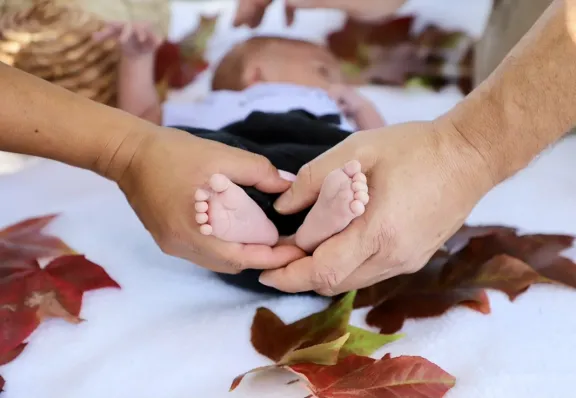 Two adult hands holding baby's feet.